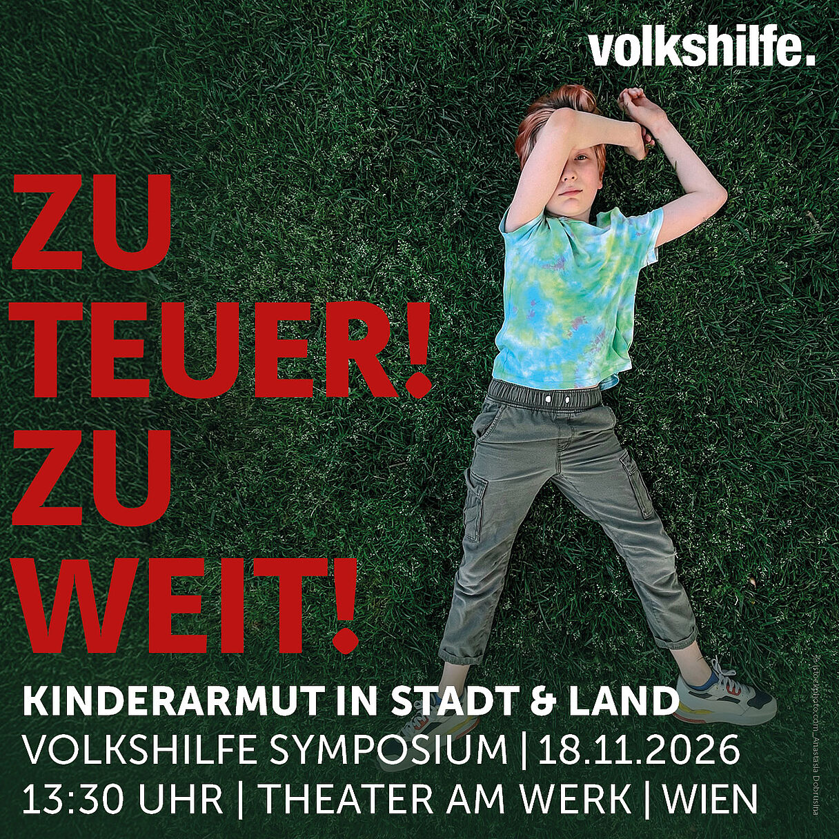 Logo und Schriftzug Save the Date: Zu teuer! Zu Weit! Kinderarmut in Stadt &amp; Land - Volkshilfe Symposium 2026, 18.11.2026, 13:30, Theater am Werk, Wien, hinter der Schrift ist ein Foto von einem Kind zu sehen. Das Kind liegt in der Wiese, den linken Arm über dem Kopf, der rechte Arm liegt neben dem Kopf in der Wiese. Das Kind Blickt in die Kamera.